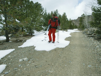 A Skier Walks Down a Dirt Road after Mountain Skiing