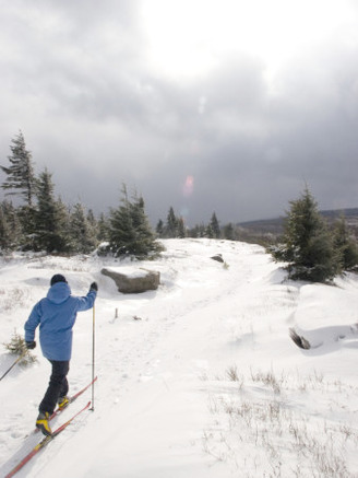 Woman Cross Country Skiing Along a Ridge Trail